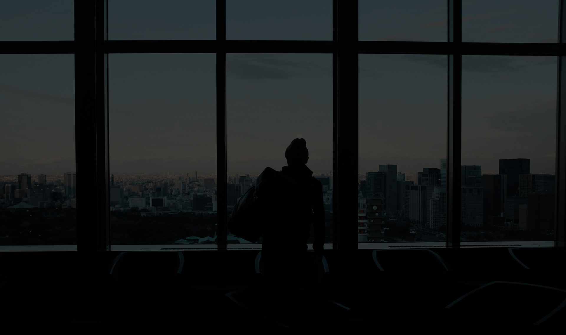 Man staring out a window overlooking a city